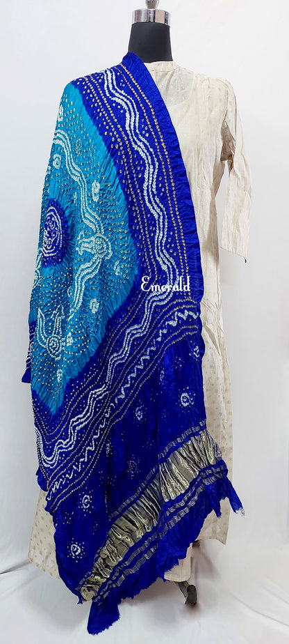 An ancient craft of 5000 years old, the term `Bandhani` is derived from the word `Bandhan' that means tying up, mainly used in the states of Gujarat and Rajasthan. This one is a light and dark blue Bandhani on pure gajji silk with gold tissue patta at both ends. A total must-have for your festive/ wedding wardrobe.