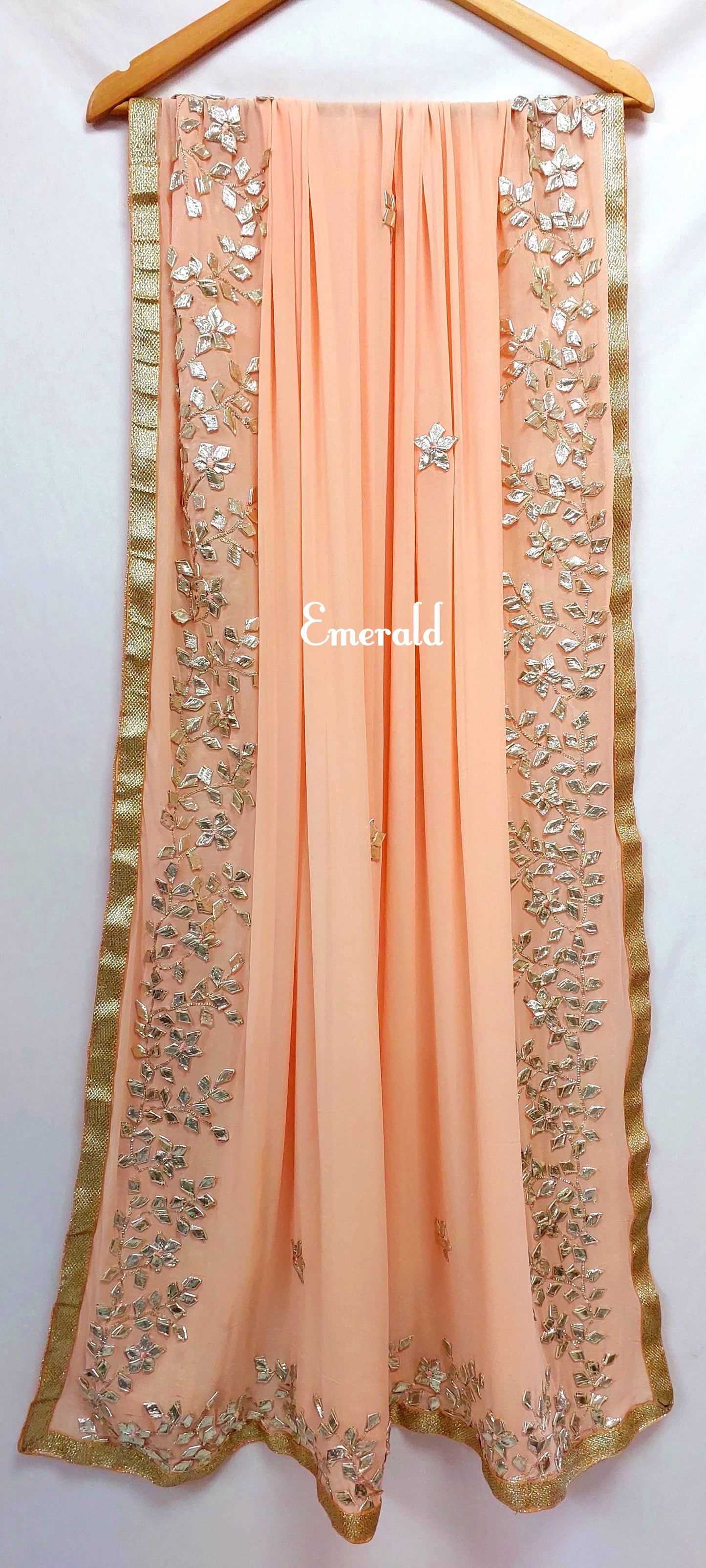 An elegant,embroidered peach Dupatta in georgette. Dupatta is bordered with a broad patch of silver gota patti work and butis in the middle area.Trimmed with an antique gold border. Perfect for any events in the wedding season!Dupatta measurements:Length-2.4mWidth-39inWash Care- Dry Clean Only.