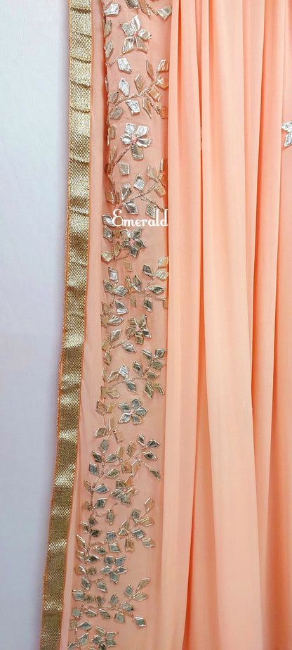 An elegant,embroidered peach Dupatta in georgette. Dupatta is bordered with a broad patch of silver gota patti work and butis in the middle area.Trimmed with an antique gold border. Perfect for any events in the wedding season!Dupatta measurements:Length-2.4mWidth-39inWash Care- Dry Clean Only.