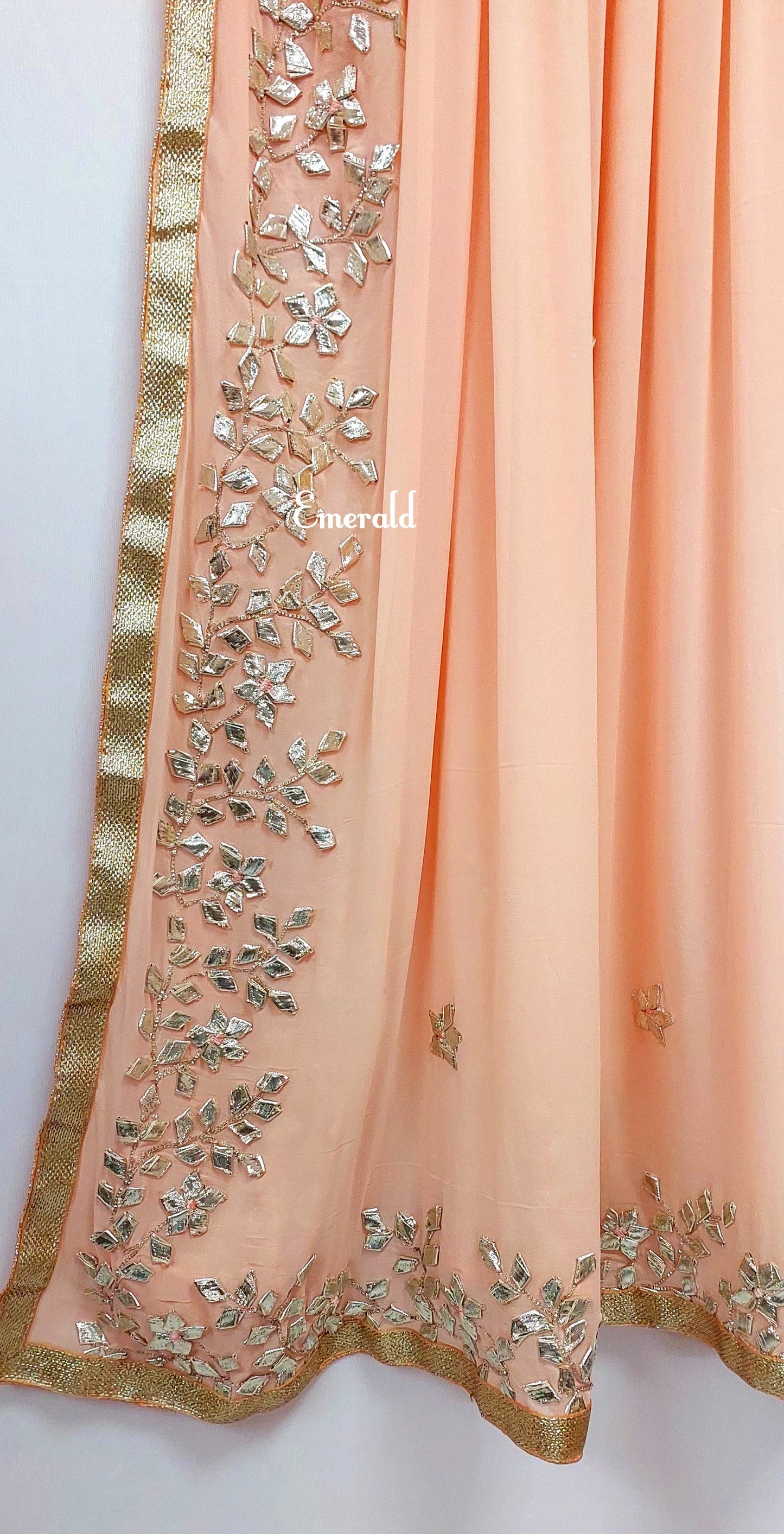 An elegant,embroidered peach Dupatta in georgette. Dupatta is bordered with a broad patch of silver gota patti work and butis in the middle area.Trimmed with an antique gold border. Perfect for any events in the wedding season!Dupatta measurements:Length-2.4mWidth-39inWash Care- Dry Clean Only.