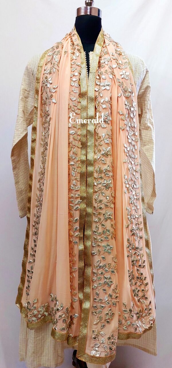 An elegant,embroidered peach Dupatta in georgette. Dupatta is bordered with a broad patch of silver gota patti work and butis in the middle area.Trimmed with an antique gold border. Perfect for any events in the wedding season!Dupatta measurements:Length-2.4mWidth-39inWash Care- Dry Clean Only.