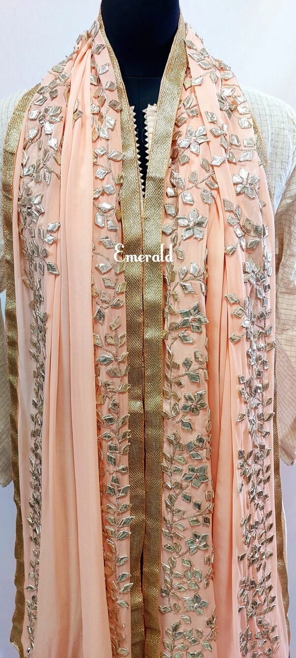 An elegant,embroidered peach Dupatta in georgette. Dupatta is bordered with a broad patch of silver gota patti work and butis in the middle area.Trimmed with an antique gold border. Perfect for any events in the wedding season!Dupatta measurements:Length-2.4mWidth-39inWash Care- Dry Clean Only.